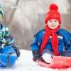 Two boys sledding in snow